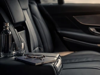 Banquette arrière en cuir avec eau, verre, carnet et lunettes, prête pour un trajet de travail