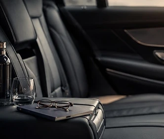 Leather rear seat with water, a glass, a notebook and glasses, ready for a working journey