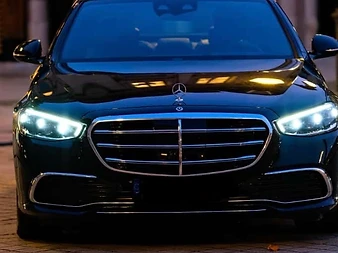 Mercedes Classe S de face, phares allumés, à la nuit tombante