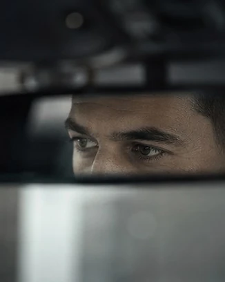 Regard d'un chauffeur concentré sur la route, vu dans le rétroviseur intérieur