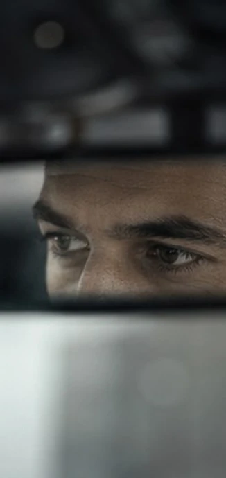 A chauffeur's focused gaze on the road, seen in the interior rear-view mirror