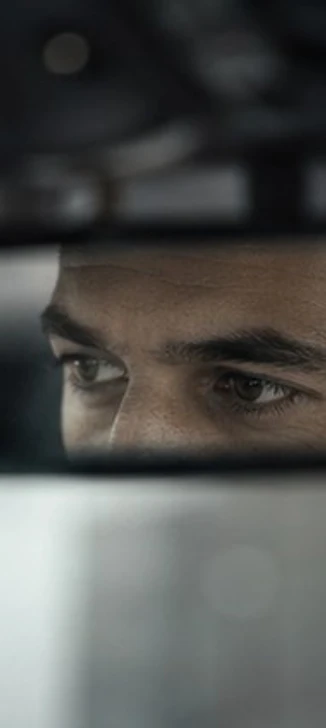 Sguardo di un autista concentrato sulla strada, visto nello specchietto retrovisore interno