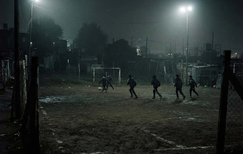 Cancha de barrio de noche, con los focos encendidos
