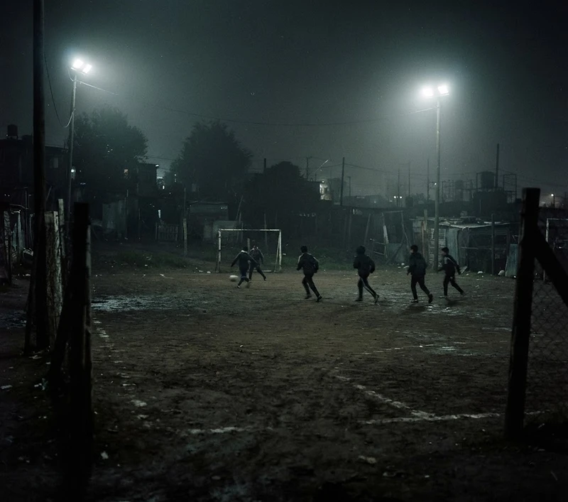 Cancha de barrio de noche, con los focos encendidos y niebla