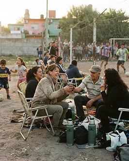 Grupo de familias alentando en la banda del partido, con mates y sillas plegables
