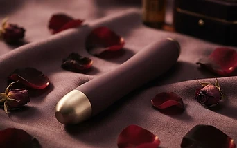 A premium intimate product on dark silk with rose petals