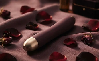 A premium intimate product on dark silk with rose petals
