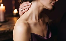 Close-up of a woman's bare neck and shoulder in warm candlelight