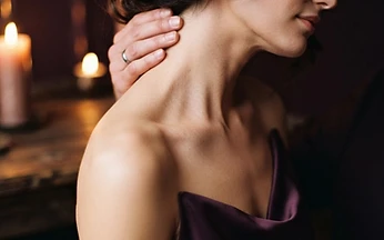 Close-up of a woman's bare neck and shoulder in warm candlelight