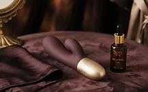 A luxury intimate toy beside folded silk on dark velvet