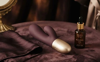 A luxury intimate toy beside folded silk on dark velvet