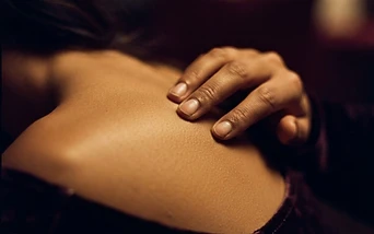 Close-up of fingertips tracing along bare skin in warm light