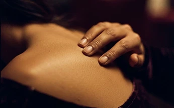 Close-up of fingertips tracing along bare skin in warm light