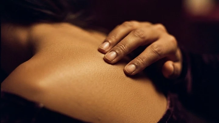 Close-up of fingertips tracing along bare skin in warm light