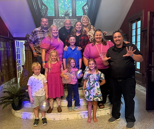 A multi-generational group of eleven posing together on an ornate marble staircase