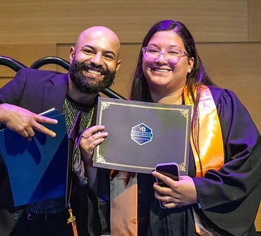 Cumbre Group founder with a YouthBuild graduate holding her certificate at commencement