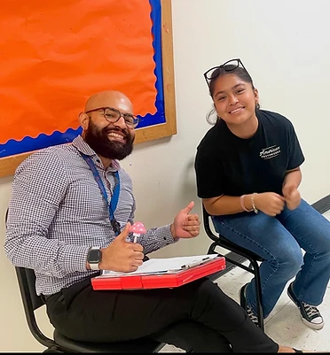 Cumbre Group team member with a YouthBuild participant reviewing program materials