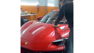 A GetRight Detailing technician machine polishing the hood of a red Ferrari with a yellow foam pad in the South Hackensack NJ shop