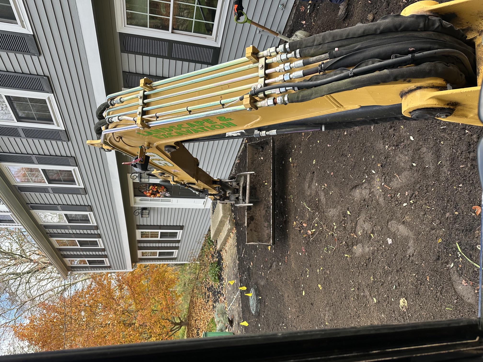 Heavy equipment regrading a sloped residential yard for proper drainage in Rhode Island