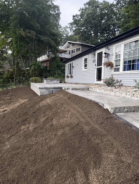 Freshly graded backyard with new loam ready for seed after a patio and regrading project in Rhode Island