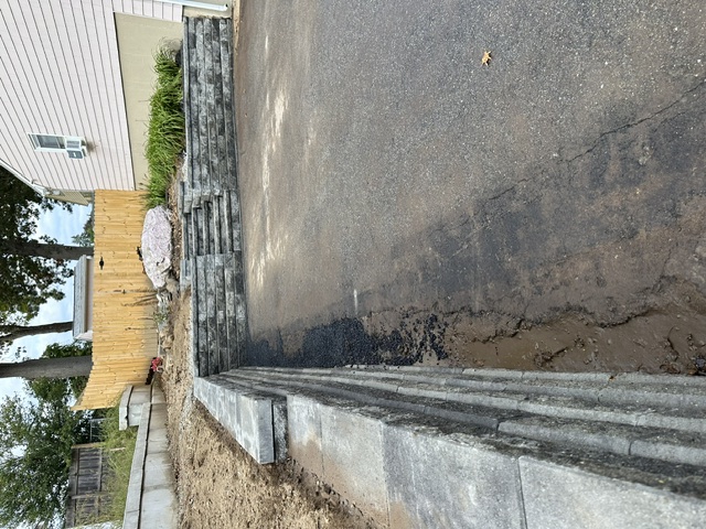 Block retaining wall with integrated steps built along a driveway in North Smithfield, RI