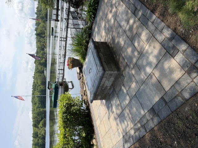 Paver patio with square stone fire pit overlooking a lake in northern Rhode Island