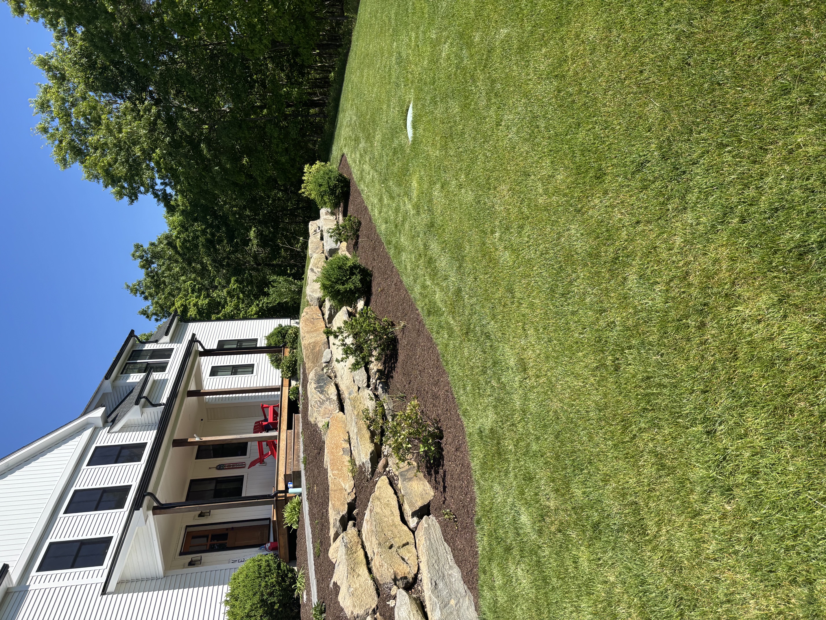 Natural boulder retaining wall installed to hold back a sloped landscape bed in Rhode Island