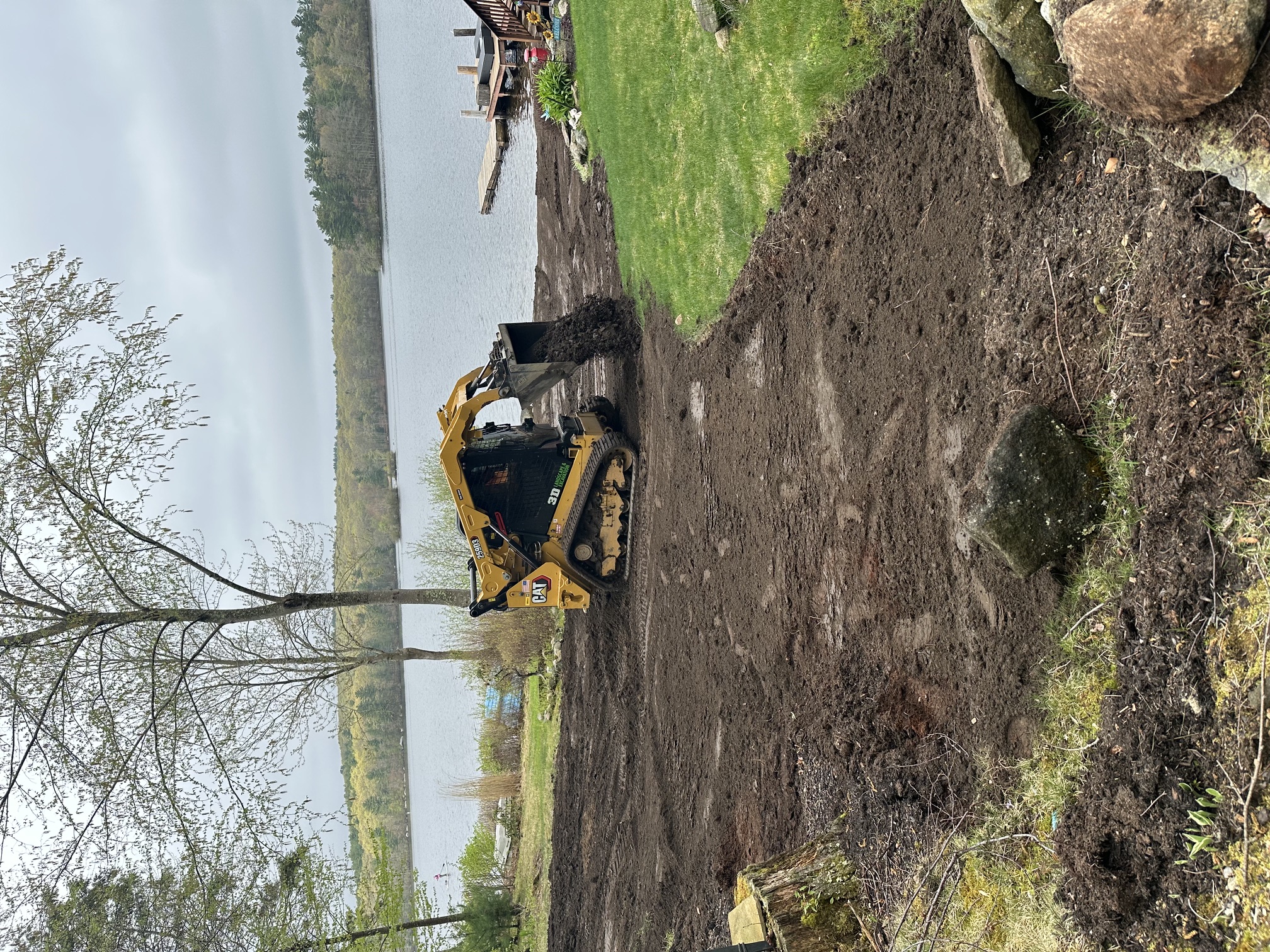 Crew spreading fresh topsoil across a graded lawn before new grass installation in Rhode Island