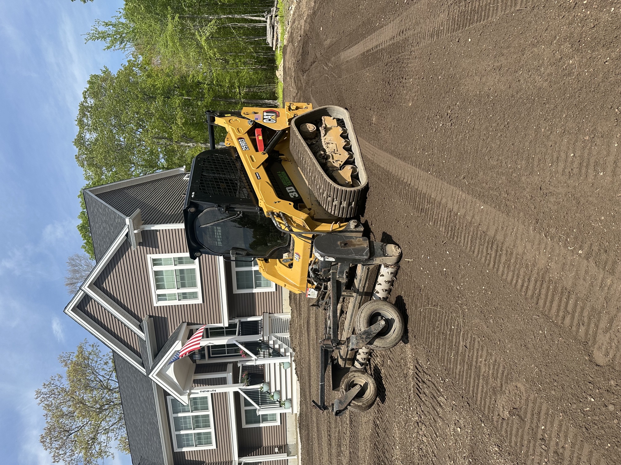 Skid steer finish grading a residential yard to prepare it for topsoil and seed in North Smithfield, RI