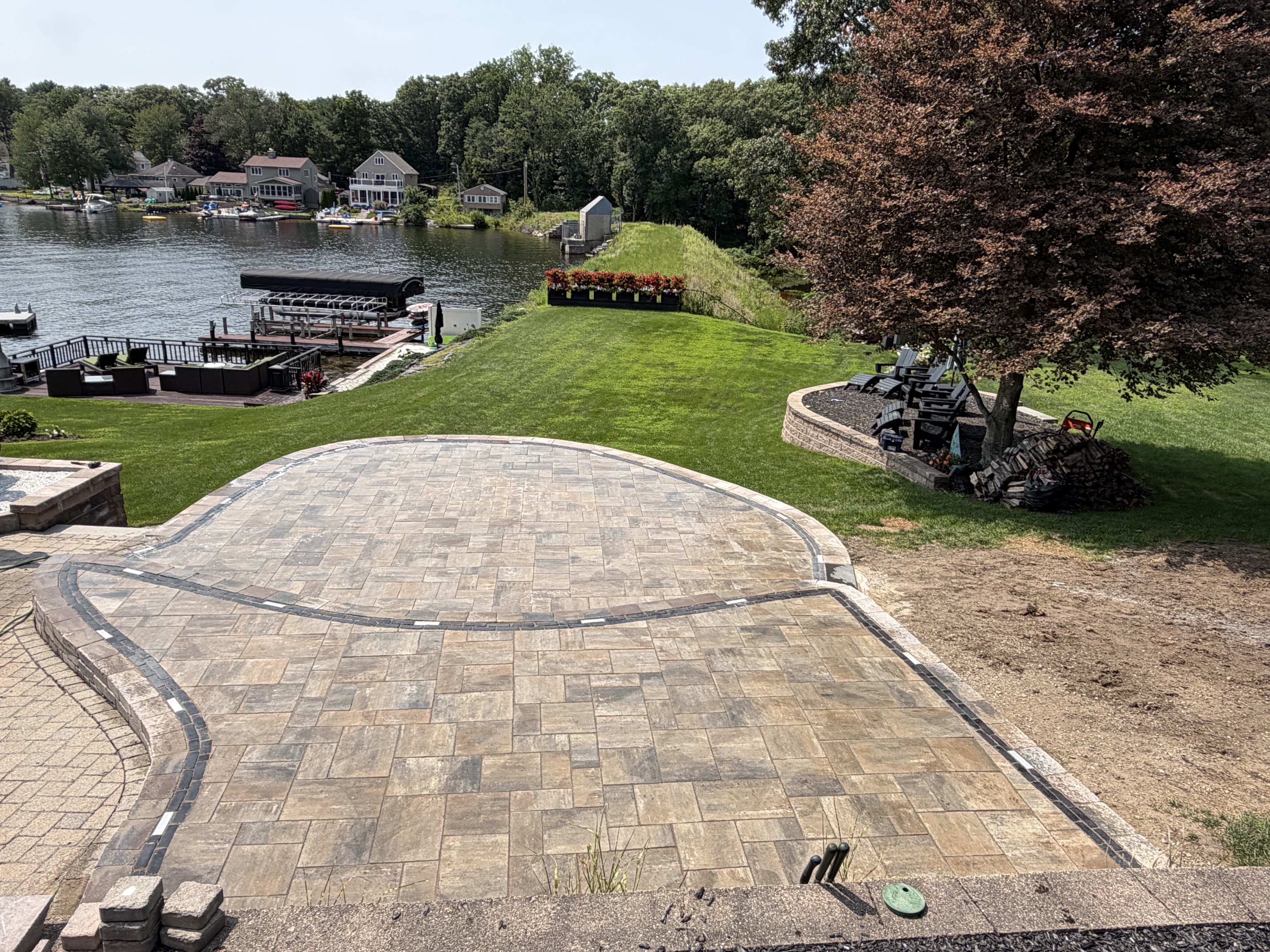 Curved paver patio overlooking a lake with custom paver border in northern Rhode Island