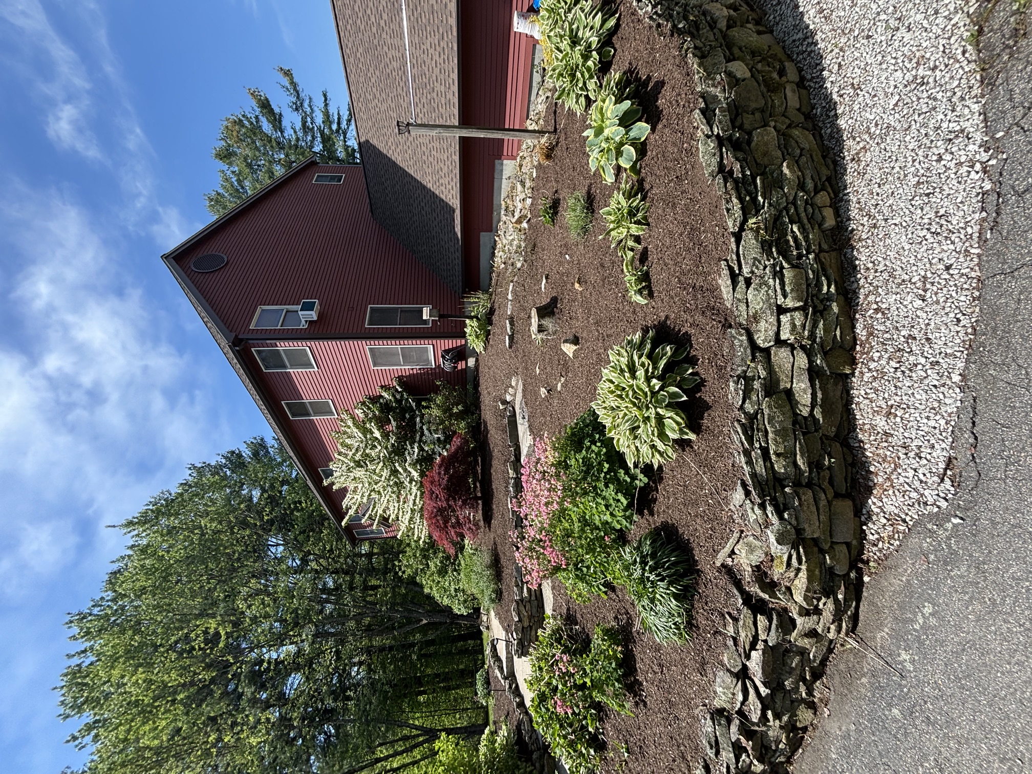 Stone garden bed edging with new plantings in a residential landscape in Rhode Island