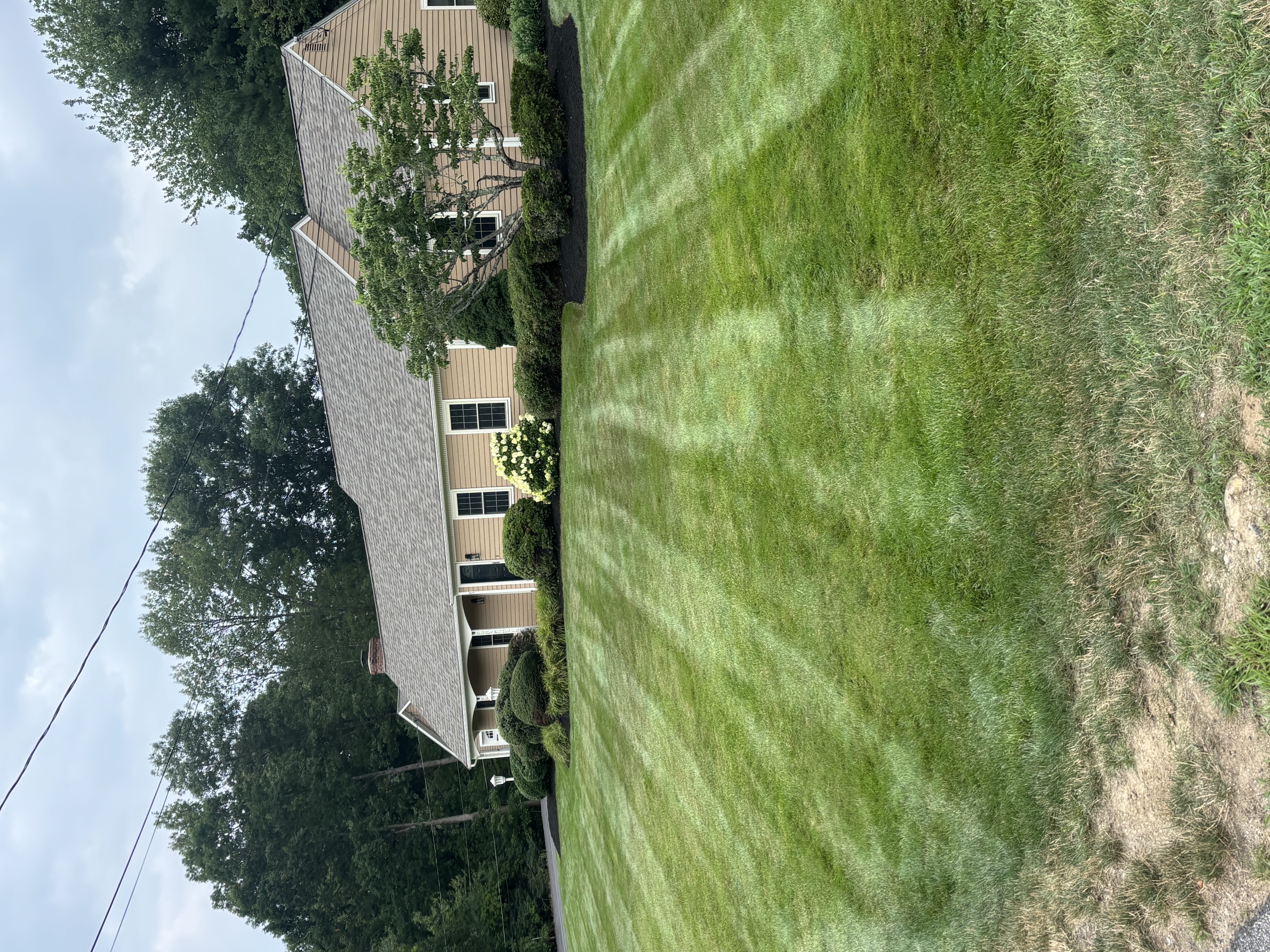 Mowed lawn with trimmed shrub beds along a home in North Smithfield, RI