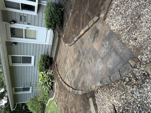 Curved front paver walkway with cobble border leading to a home entrance in North Smithfield, RI