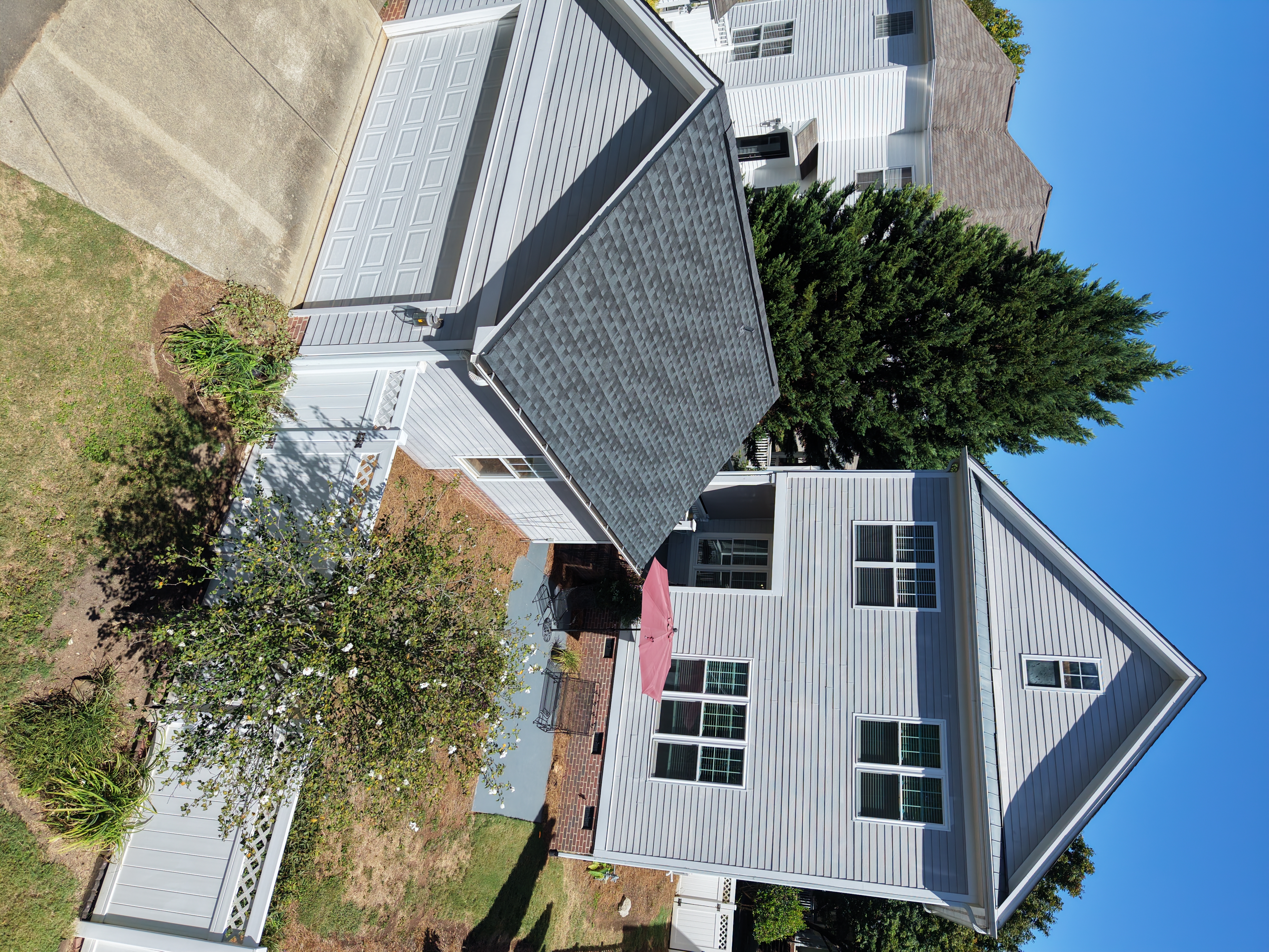 Aerial view of the back of a two-story home with garage and fenced patio