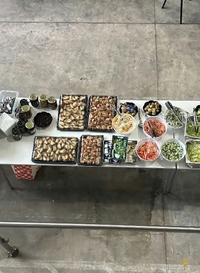 A long catering table laid with salads, pastries, deli platters and fruit for an event