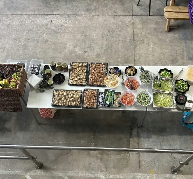 A long catering table laid with salads, pastries, deli platters and fruit for an event