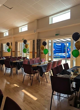 Our hall laid with tables, black cloths and balloon centrepieces before a party