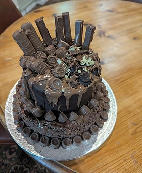 A tiered chocolate celebration cake finished with chocolate bars and drips