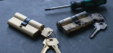 Nieuwe cilinder met sleutels naast de versleten cilinder die vervangen wordt