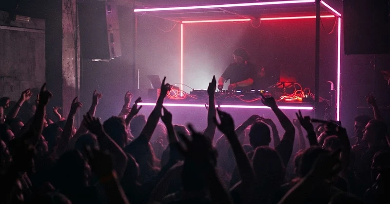 Dj achter de draaitafels in paars neonlicht