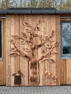 Geschnitztes Baum-Motiv an einer senkrechten Holzfassade
