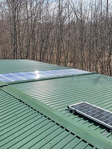 Grünes Blechdach mit Lichtbändern und montiertem Solarmodul