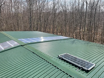 Grünes Blechdach mit Lichtbändern und montiertem Solarmodul