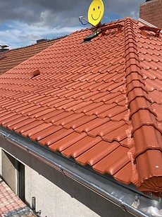 Terrakotta-Ziegeldach mit Firstlinie, gemauertem Schornstein und Satellitenschüssel