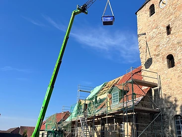 Hubarbeitsbühne hebt Material zu den Dacharbeiten an einem Steinturm
