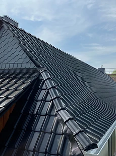 Glasiertes dunkles Ziegeldach mit Schornstein und Schiefergaube