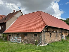 Neu eingedecktes rotes Ziegeldach auf einem sanierten Steinhaus