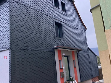 Dunkle Schiefer-Schindelfassade an einem Wohnhaus