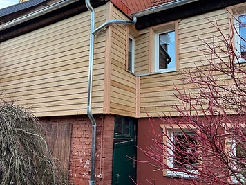 Saniertes Haus mit Sichtmauerwerk im Erdgeschoss und Holzverkleidung im Obergeschoss