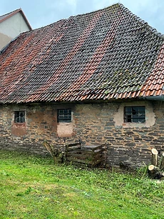 Historisches Steingebäude mit marodem Ziegeldach vor der Sanierung